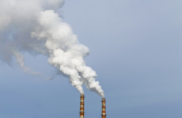 Coal power plant smokestacks emit carbon dioxide pollution by factory under blue sky