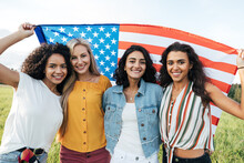 Group Of Multi-ethnic Women Holding A USA Flag. Female Friends Celebrating Independence Day.