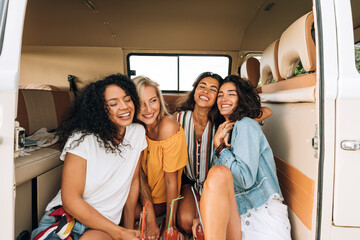 Wall Mural - Happy young women sitting together in camper van enjoying vacation