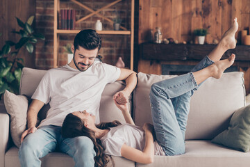 Wall Mural - Portrait of attractive cheerful couple soulmates sitting on divan enjoying having fun talking at loft style interior home house indoor