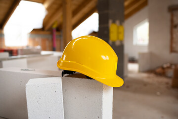 Still life of a yellow protective helmet lying on construction site in an attic with other utensils