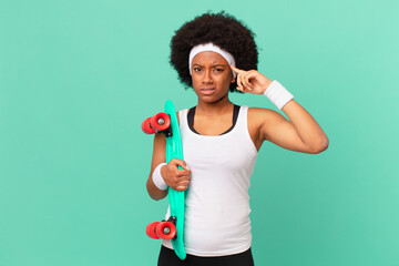 afro woman feeling confused and puzzled, showing you are insane, crazy or out of your mind. skateboard concept