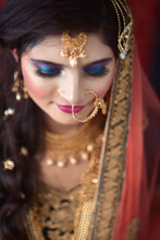 Portrait Of An Elegant Indian Model In Bridal Look With Heavy Gold Jewelry And Red Sari.