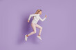© Tetiana - Profile photo of positive sportive lady jump run wear white jumper posing on purple background