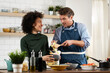 © JustLife - Happy smiling couple cooking together. Husband and wife preparing delicious food