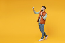 Full Length Young Smiling Friendly Man In Orange Vest Mint Sweatshirt Glasses Do Selfie Shot On Mobile Phone Show Victory V-sign Gesture Isolated On Yellow Background Studio. People Lifestyle Concept.