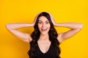 Poster - Photo of young excited girl happy positive smile amazed surprised sale news hands touch head isolated over yellow color background