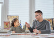 © boytsov - Happy beautiful caucasian family creative art hobby and funny time spending together. Sitting at the table drawing together and showing each other thumbs up gesture. High quality image