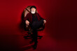 © deagreez - Full size photo of aged person sit in leather chair look interested camera isolated on dark red color background
