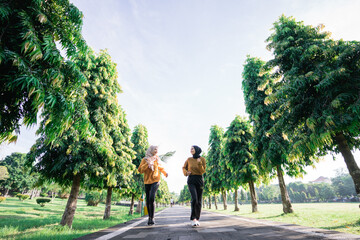 view from below of two girls in veil do outdoor sports while jogging together in the garden with copyspace