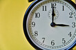 Shot of vintage retro analog clock on yellow background showing 3 o clock