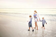 © Christin Lola - Mother and Children Walking Along Ocean Beach at Sunset