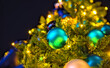 Night view of a spherical blue Christmas ornament on a Christmas tree illuminated by yellow lights