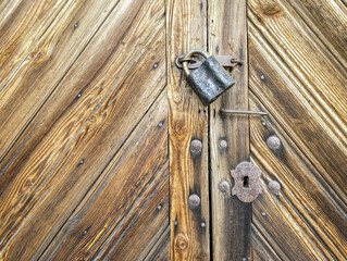 closed wooden door with rusty padlock. diagonal planks with natural pattern