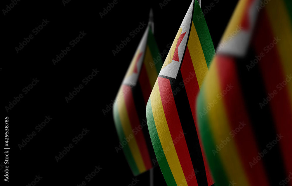 Small national flags of the Zimbabwe on a black background - obrazy, fototapety, plakaty 