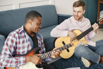 African man and Caucasian man playing guitar