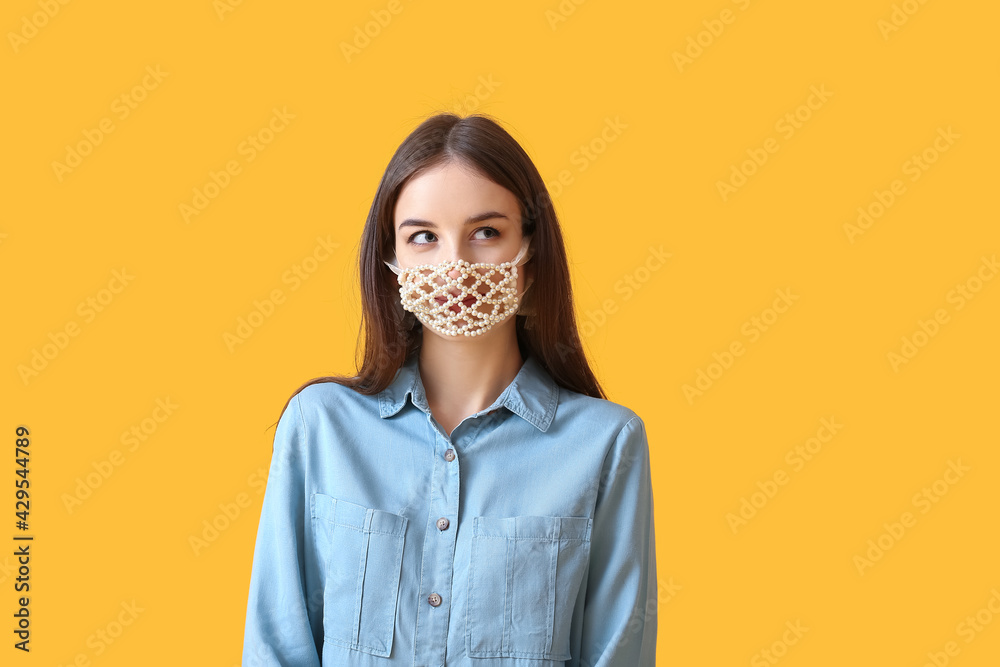 Stylish young woman wearing creative mask on color background