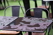 Close-up Of Wet Iron Tables And Chairs Perched On The Garden Lawn.