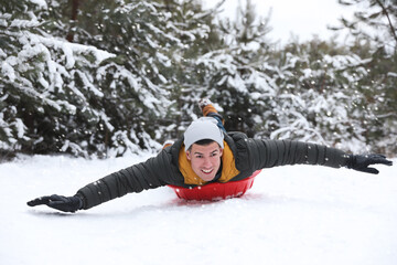 Wall Mural - Happy man sledding outdoors on winter day. Christmas vacation