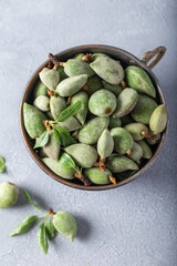 Wall Mural - Bowl of fresh unripe almonds on gray background.  Fresh raw green almonds in a metal bowl. Top view.