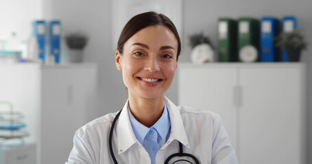 Portrait of smiling female doctor wearing white coat with stethoscope in hospital office