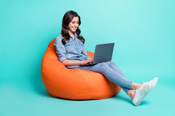 Canvas Print - Photo of adorable pretty young lady dressed denim shirt sitting beanbag typing modern gadget isolated teal color background