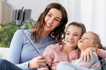 Wall Mural - family, technology and people concept - happy mother and daughter with smartphone taking selfie at home