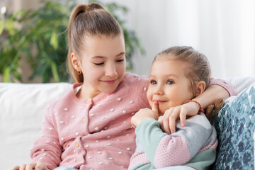 Wall Mural - family, childhood and friendship concept - two happy smiling little girls or sisters at home