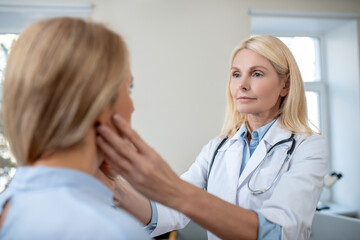 Doctor touching patients neck with his hands