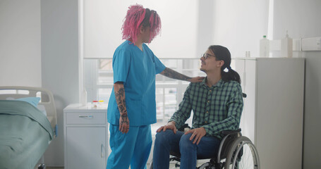 Caring female nurse talking to disabled patient in hospital