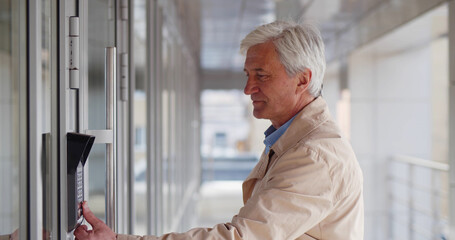 Senior man put finger on electronic control machine to access digital door locking system.