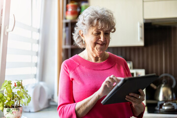 Wall Mural - Happy senior woman using digital tablet at home
