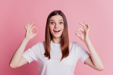 Funny promoter lady show two okey signs over pink background