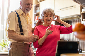 Wall Mural - Happy senior couple using digital tablet at home
