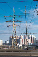 High voltage tower against a blue sky and city background