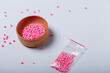 © elenaseiryk - Wooden bowl  and small package of pink beads for sewing and embroidery on white background. Set of materials for handcraft, making of bijouterie and accessories. Copy space.