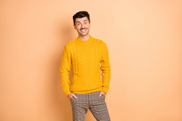 Poster - Photo portrait of smiling man with hands in pockets isolated on pastel beige colored background