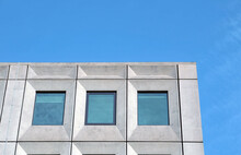 perspective view of a white concrete office building against a bright blue sky with geometric brutalist 1960s details