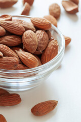 Almond nuts in the glass bowl om the white table close up