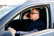 © F8  \ Suport Ukraine - Cheerful man wearing eyeglasses sitting on the drivers seat and talking with his wife on the phone.