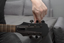 Black Electric Guitar Tuning. Fingers Are Turning The Tuning Peg. Hand In The Frame. Learning To Play The Guitar.