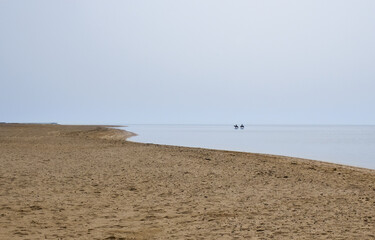 Silhouettes of two horsemen are set against the backdrop of the sea and a deserted sandy beach. Egypt. 