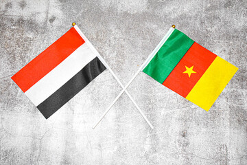 Hand flags of Yemen and Camerun on Abstract background