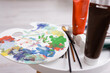 © LIGHTFIELD STUDIOS - paintbrushes and palette near tubes with paint on coffee table