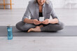 © LIGHTFIELD STUDIOS - cropped view of middle aged woman sitting in lotus pose on yoga mat and using smartphone