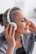 © LIGHTFIELD STUDIOS - happy middle aged woman listening music in in wireless headphones
