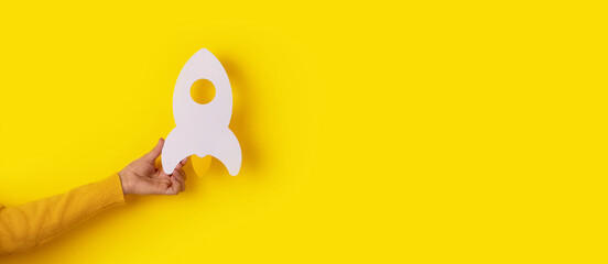 rocket in hand over yellow background, startup business idea, panoramic mock-up