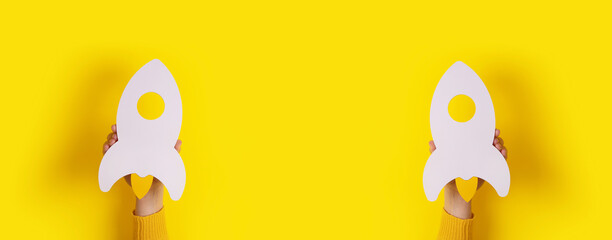 rockets in hand over yellow background, panoramic image with space for text in centre