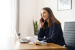 © Vadim Pastuh - Executive female office employee takes a phone call sitting on the workplace, smiling young woman has pleasant phone conversation, talking and chatting on the smartphone in the office