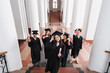 © LIGHTFIELD STUDIOS - High angle view of cheerful asian graduate holding diploma near friends in caps